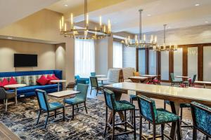 a lobby with tables and chairs and a couch at Hampton Inn & Suites Raleigh Midtown, NC in Raleigh