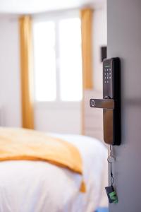 un téléphone suspendu sur un mur à côté d'un lit dans l'établissement **Auberge de l'Aude**, à Carcassonne