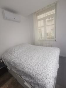 a bed in a white room with a window at Très bel appartement climatisé à deux pas de la cathédrale in Reims
