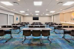 an empty room with tables and chairs and a tv at Home2 Suites By Hilton Battle Creek, Mi in Battle Creek