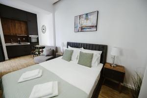 a bedroom with a large white bed and a kitchen at M & N Guesthouse in Volos