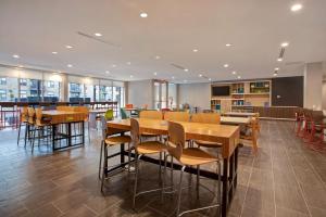 a restaurant with wooden tables and chairs in a cafeteria at Home2 Suites By Hilton Carmel Indianapolis in Carmel