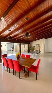 a dining room with a wooden table and red chairs at Recanto das Araras, Transcendental in Bonito