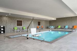 a pool in a hotel room with chairs and tables at Home2 Suites By Hilton Norfolk Airport in Norfolk