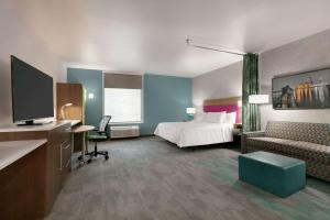 a hotel room with a bed and a tv at Home2 Suites By Hilton Norfolk Airport in Norfolk