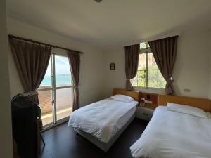 a bedroom with two beds and a large window at 富喜民宿二館 in Nangan