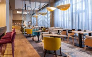 a restaurant with tables and chairs and windows at Hampton By Hilton Krasnodar in Krasnodar