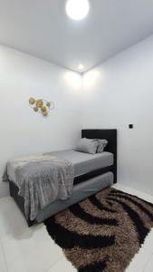 - un lit dans une chambre blanche avec un tapis dans l'établissement Mountain Hill, à Songgoriti