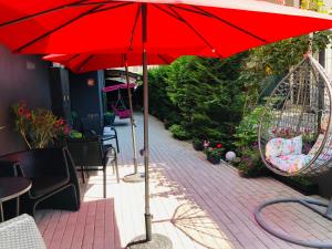 een rode parasol op een patio met stoelen en een schommel bij Colors Boutique in Obzor