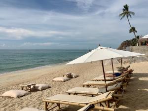 a group of lounge chairs and an umbrella on a beach at 4U Resort Samui in Lamai