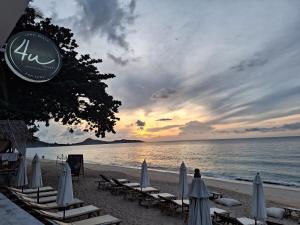 a beach with chairs and umbrellas and the ocean at 4U Resort Samui in Lamai