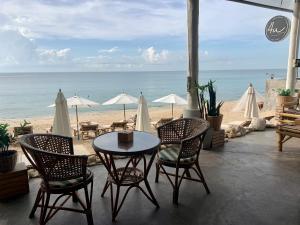 a table and chairs and a beach with umbrellas at 4U Resort Samui in Lamai