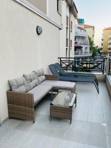 a patio with a couch and tables on a balcony at Golden Sea View New in Pomorie
