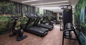 a row of tread machines in a gym with a painting at DoubleTree By Hilton A Coruña in A Coruña