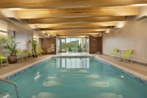 Home2 Suites By Hilton Ephrata في إفراتا: مسبح في فندق وكراسي خضراء وسقف