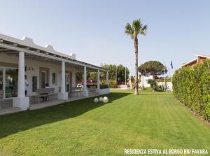 een huis met een tuin met twee ballen op het gazon bij Residenza estiva al Borgo Rio Favara in Santa Maria Del Focallo