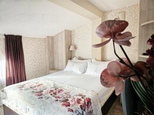 Villa Magnolia في سوزوبول: غرفة نوم عليها سرير مع وردة
