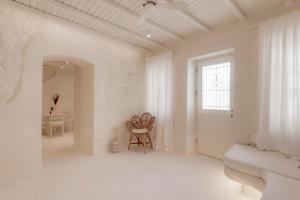 a white room with a chair and a window at White Suites in Ermoupoli