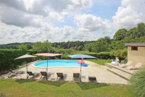 a pool with chairs and umbrellas in a yard at Hamlet retreat in Ladignac-le-Long