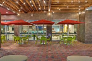 a restaurant with tables and chairs with red umbrellas at Home2 Suites Corpus Christi Southeast, Tx in Corpus Christi