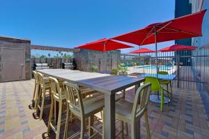 einen Tisch und Stühle mit roten Sonnenschirmen auf einer Terrasse in der Unterkunft Home2 Suites Corpus Christi Southeast, Tx in Corpus Christi