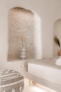 a white bedroom with a bed and a table at White Suites in Ermoupoli