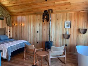 a bedroom with a bed and two chairs and a table at Refúgio de Altitude - Centro in Urupema