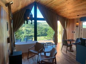 a room with a table and chairs and a large window at Refúgio de Altitude - Centro in Urupema