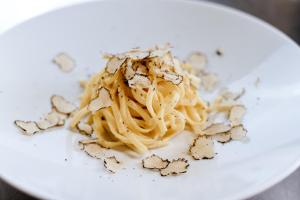 a white plate with pasta and cheese on it at Bella Hotel & Restaurant with private dock for mooring boats in San Felice del Benaco