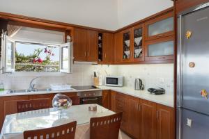 cocina con armarios de madera, mesa y nevera en Anna House, en Panteli