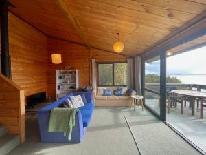 uma sala de estar com um sofá azul e uma mesa em Hekerua Bay Views Oneroa - Waiheke Escapes em Oneroa