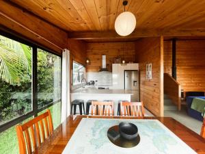 uma cozinha em plano aberto e sala de jantar com mesa e cadeiras em Hekerua Bay Views Oneroa - Waiheke Escapes em Oneroa