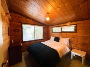 um quarto com uma cama num chalé de madeira em Hekerua Bay Views Oneroa - Waiheke Escapes em Oneroa