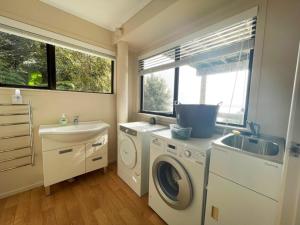 uma lavandaria com um lavatório e uma máquina de lavar roupa em Hekerua Bay Views Oneroa - Waiheke Escapes em Oneroa