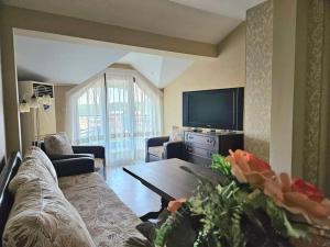 a living room with a couch and a tv at Villa Magnolia in Sozopol