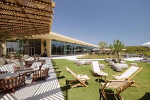 a patio with lounge chairs and tables and a building at Verdelago Resort in Praia Verde