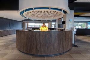 a woman is standing behind a counter in a lobby at Tru By Hilton Grantville, Pa in Grantville