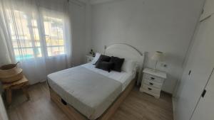 een witte slaapkamer met een bed met zwarte kussens bij Corazón de Alicante con vistas al mar y al castillo in Alicante