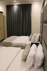 two beds in a hotel room with white pillows at تاج الحمراء للاجنحة الفندقية Taj Al Hamra Hotel Suites in Riyadh