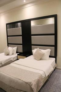 a bedroom with two beds with white sheets at تاج الحمراء للاجنحة الفندقية Taj Al Hamra Hotel Suites in Riyadh