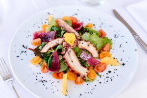 a white plate with a salad with shrimp and vegetables at Bella Hotel & Restaurant with private dock for mooring boats in San Felice del Benaco