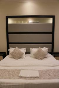 a large bed with white sheets and pillows at تاج الحمراء للاجنحة الفندقية Taj Al Hamra Hotel Suites in Riyadh