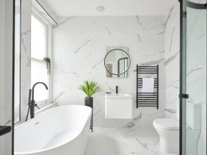 a white bathroom with a tub and a toilet at Fulham - Hestercombe House by Viridian Apartments in London