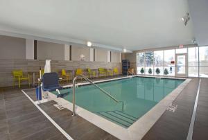 ein Pool in einem Gebäude mit gelben Stühlen in der Unterkunft Home2 Suites By Hilton Richmond in Richmond