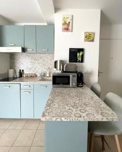 a kitchen with blue cabinets and a counter with a microwave at MENTHE et CITRON entre DISNEY et PARIS in Villiers-sur-Marne