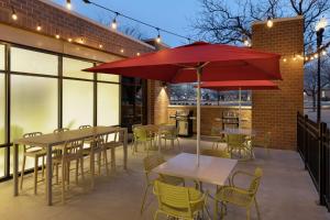 a patio with tables and chairs and a red umbrella at Home2 Suites By Hilton Ogden in Ogden