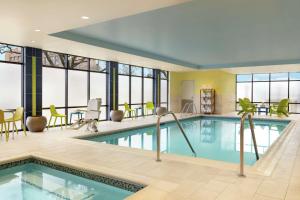 a hotel pool with chairs and a tables and chairs at Home2 Suites By Hilton Ogden in Ogden