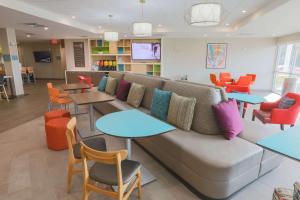 a waiting room with a couch and tables and chairs at Home2 Suites By Hilton Cumming Atlanta, Ga in Cumming