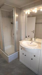 a white bathroom with a sink and a shower at Ferienwohnung Achterdeck - Alte Schmiede Neugarmssiel in Wangerland +24 photos