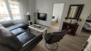 een woonkamer met een bank en een tv bij Corazón de Alicante con vistas al mar y al castillo in Alicante